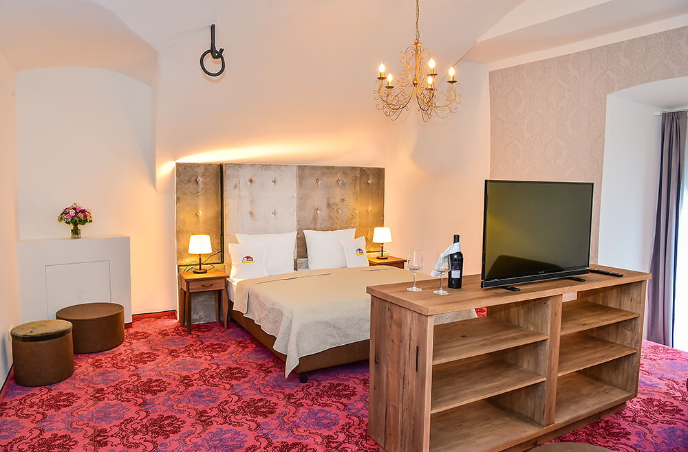 Ansicht der München-Suite mit Bett und TV Set